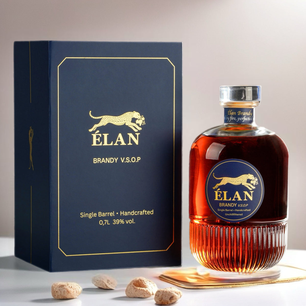 Eine Flasche Élan Brandy V.S.O.P. und ihre blaue Schachtel, im Vordergrund liegen verstreute Mandeln.