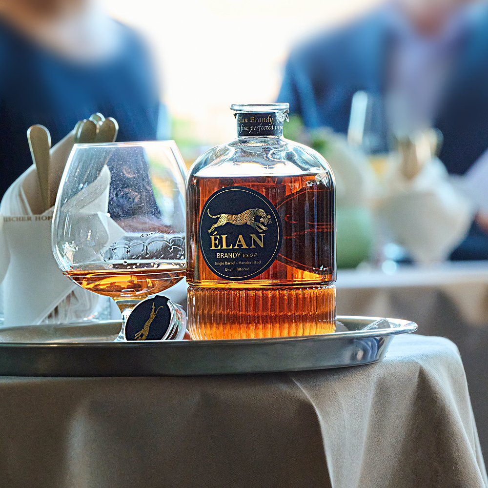 Eine Flasche Élan-Brandy und ein Brandy-Glas auf einem Silbertablett.